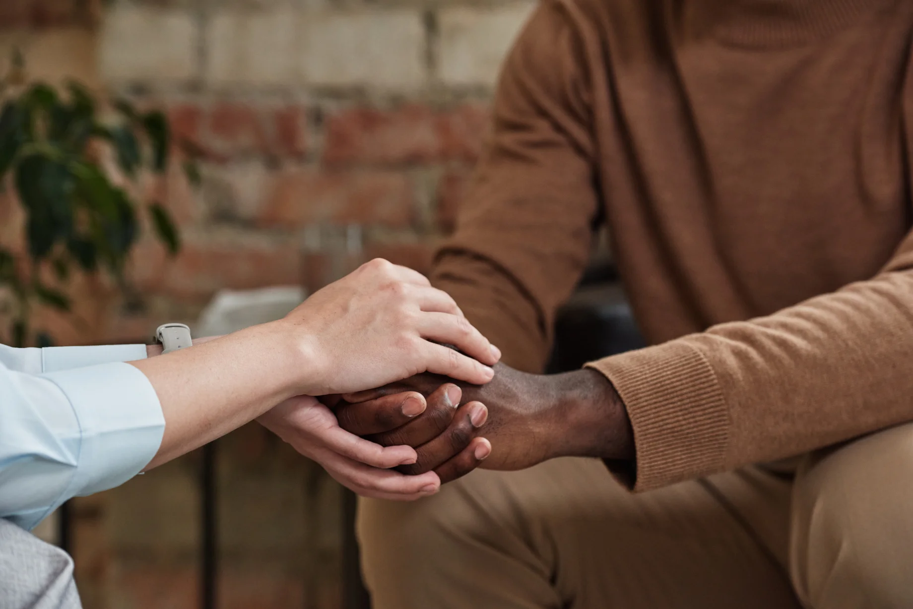 A person comforting another by taking their hands