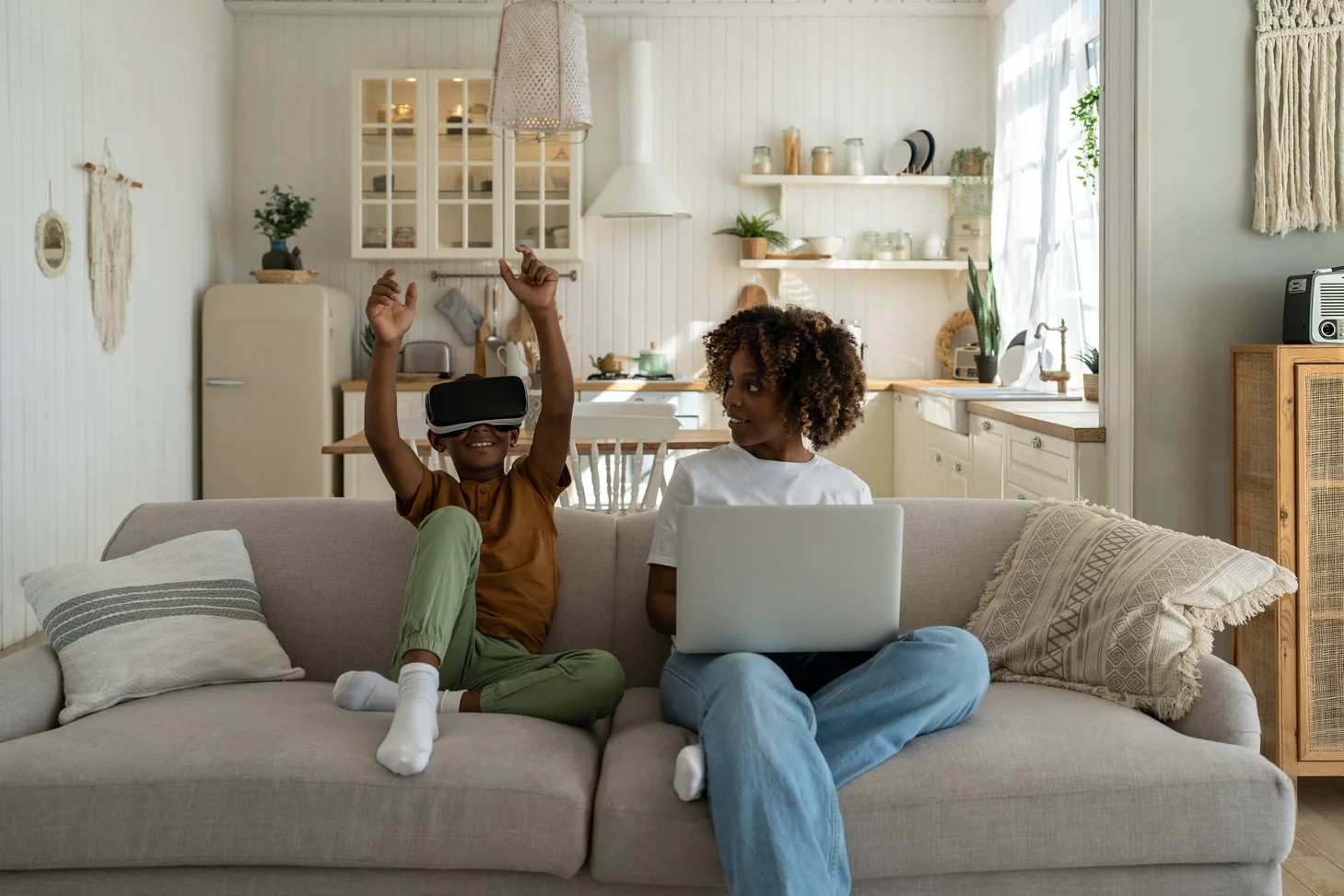 A child with a VR headset on, sitting next to a woman on a laptop